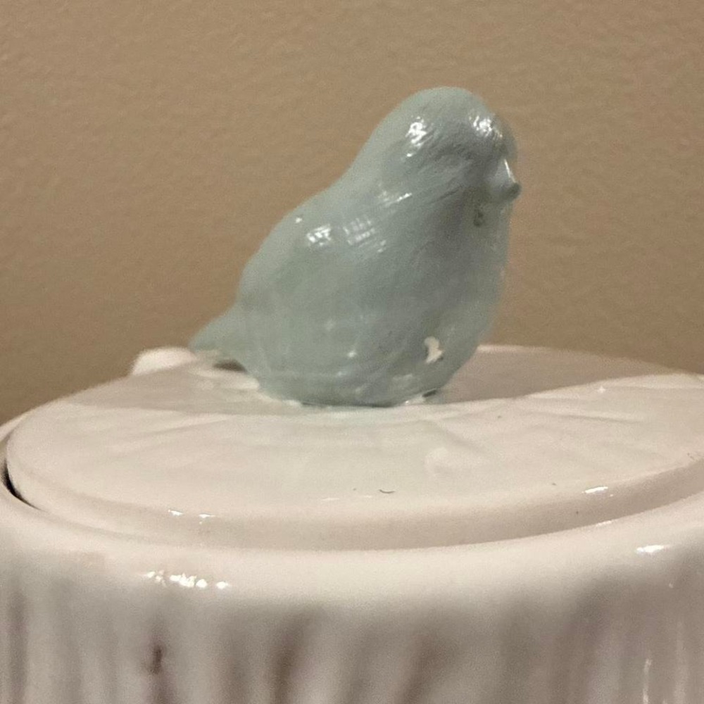 Blue ceramic bird figurine on a white ceramic base